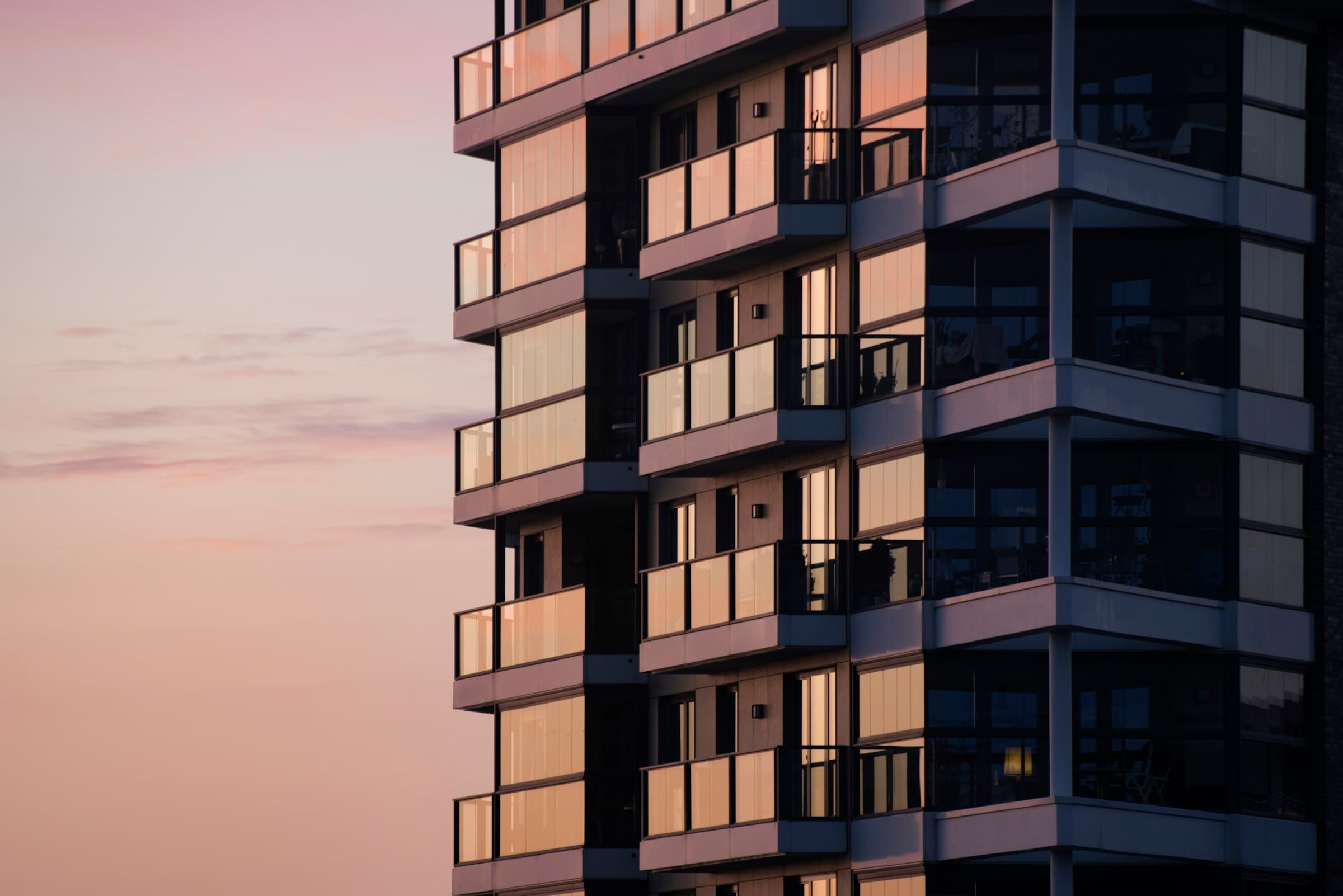 A residential tower's glass balconies lit gold at dusk — illustrative.